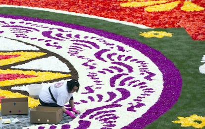 Un voluntario trabaja en un parte de la alfombra de flores