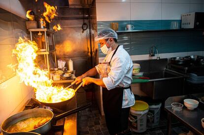 Un cocinero prepara lomo saltado en la cocina de un restaurante de Lima (Perú). Algunos locales de ocio del país han reabierto sus puertas tras cuatro meses de cierre por la pandemia de coronavirus.