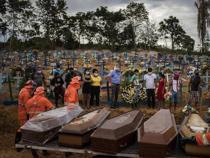 Un grupo de personas asiste a un sepelio en una tumba colectiva en Brasil.