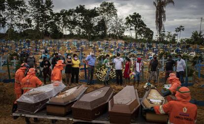 Un grupo de personas asiste a un sepelio en una tumba colectiva en Brasil.