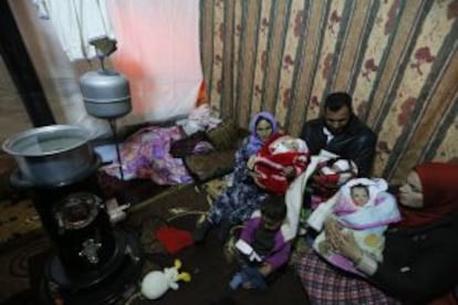 Un refugiado sirio sostiene, con la ayuda de su madre y su hermana, a sus trillizos recién nacidos en un parto en el que murió su esposa.