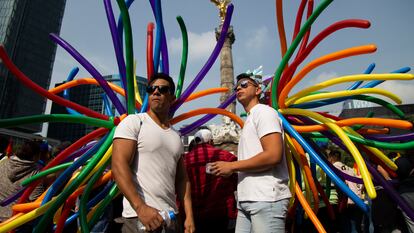 Dos asistentes esperan el inicio de la marcha del orgullo LGBT+ en el Paseo de la Reforma, en Ciudad de México, en junio de 2022.