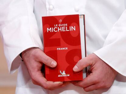 Un chef sostiene la Guía Michelin 2018.