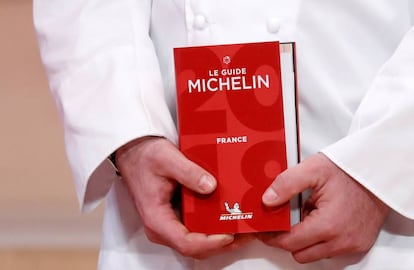 Un chef sostiene la Guía Michelin 2018.