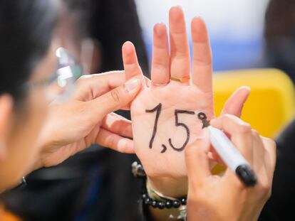 Activistas se pintan en las manos "1,5 grados", el objetivo del Acuerdo de París, en la cumbre de Clasgow.