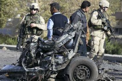 Soldados estadounidenses y policías iraquíes examinan los restos del coche de uno de los suicidas en Bagdad.