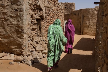 Mujeres caminando por la ciudad antigua de Chinguetti, que conserva el trazado urbano característico de las ciudades caravaneras y la técnica constructiva tradicional de casas de piedra.
