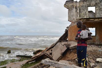 Um homem com seu filho em Grand Lahou, uma cidade de Costa de Marfim que corre o perigo de desaparecer no mar devido à mudança climática.