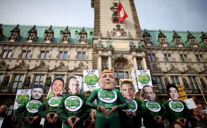 Los miembros de la asociación cívica Avaaz cubiertos con caretas de la canciller alemana, Angela Merkel, y otros jefes de Estado y de Gobierno durante una acción para que solo se utilice energía limpia, en Hamburgo, Alemania.