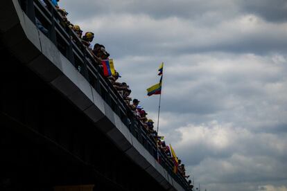 Personas observan desde un puente el paso de la manifestación.