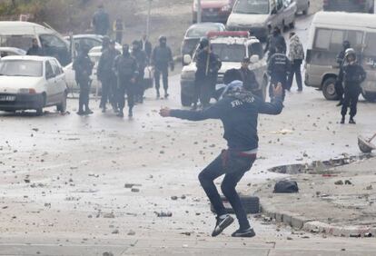 Un manifestante lanza piedras contra la policías en las cercanías del cementerio donde ha sido enterrado el opositor Belaid.