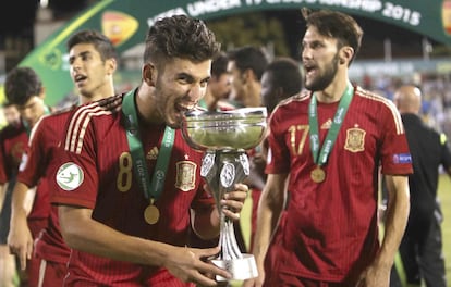 El bético Dani Ceballos muerde el trofeo del Campeonato Europeo sub-19 de 2015 en presencia de sus compañeros Marco Asensio (i) y Alfonso Pedraza (d).