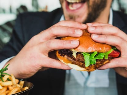 Un hombre come en una hamburguesería. Algunas multinacionales han aprovechado la pandemia para aumentar sus ganancias vendiendo productos poco saludables.