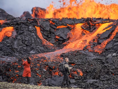 People look at the lava flowing on Fagradalsfjall volcano in Iceland on Wednesday Aug. 3, 2022, which is located 32 kilometers (20 miles) southwest of the capital of Reykjavik and close to the international Keflavik Airport. (AP Photo/Marco Di Marco)