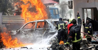 Bomberos somalíes intentan apagar el fuego ocasionado por la explosión de un coche bomba cerca de un restaurante, en Mogadiscio.