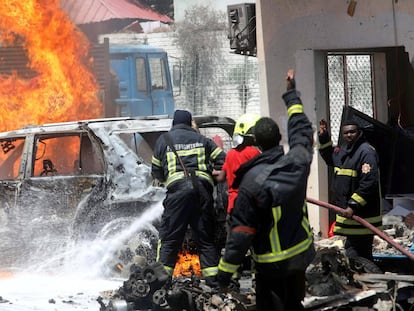 Bomberos somalíes intentan apagar el fuego ocasionado por la explosión de un coche bomba cerca de un restaurante, en Mogadiscio.