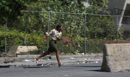 Una mujer corre para protegerse de los disparos durante los enfrentamientos entre la policía y las pandillas en el barrio de Delmas en Puerto Príncipe, Haití, el lunes 2 de diciembre de 2024. 