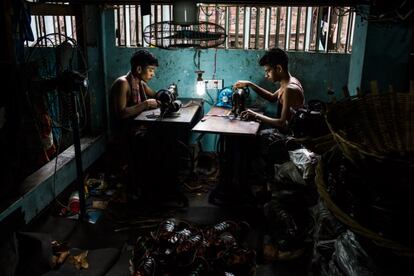 Dos jóvenes trabajan cosiendo zapatillas en un taller textil situado en el barrio viejo de Daca. Allí desarrollan jornadas de cuarenta horas a la semana por el sueldo más bajo del planeta, unos 38 euros al mes.