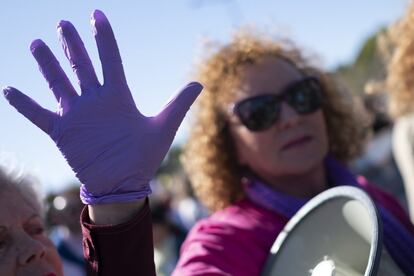 Una mujer levanta la mano con un guante morado, durante la manifestación en Sevilla del 8-M.