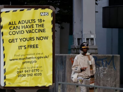 Um homem passa junto a um cartaz que estimula a população a se vacinar contra a covid-19, nesta segunda-feira, em Manchester (Reino Unido).