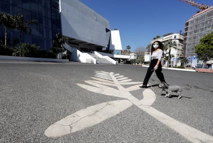 Una mujer lleva una máscara ante un símbolo de la Palma de Oro pintado en el paseo de la Croisette, donde se celebra el Festival de Cannes, en Francia, el pasado 18 de marzo .