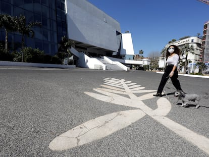 Una mujer lleva una máscara ante un símbolo de la Palma de Oro pintado en el paseo de la Croisette, donde se celebra el Festival de Cannes, en Francia, el pasado 18 de marzo .