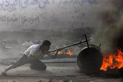 Un activista palestino se parapeta detrás de un bidón en llamas en Beit Lahia para disparar sobre las tropas israelíes con un fusil artesanal.