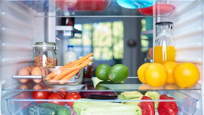 Opened fridge from the inside full of vegetables, fruits and other groceries.