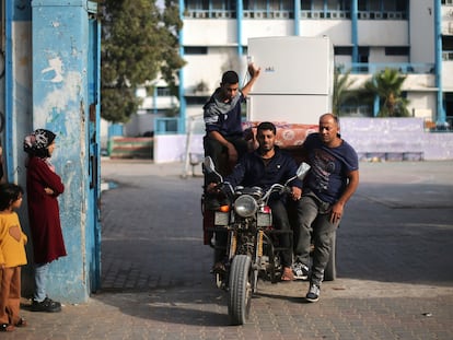 Varios palestinos trasladan este viernes en una moto sus pertenencias tras abandonar la escuela de Naciones Unidas donde estaban refugiados en Gaza.