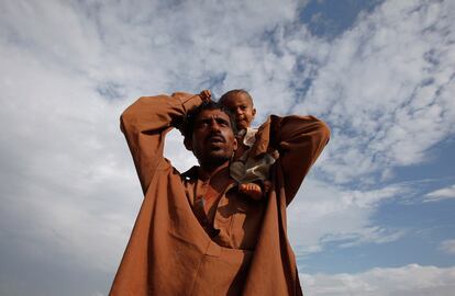 Una víctima de las inundaciones en Pakistán lleva a su hijo a hombros en un campo de refugiados de Sukkur, en la provincia de Sindh.