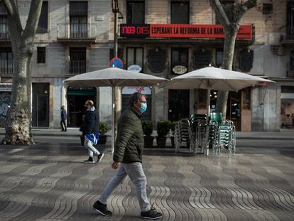 Varias personas caminan por la Rambla, de fondo, el cartel que recuerda los días transcurridos desde que se anunció la reforma