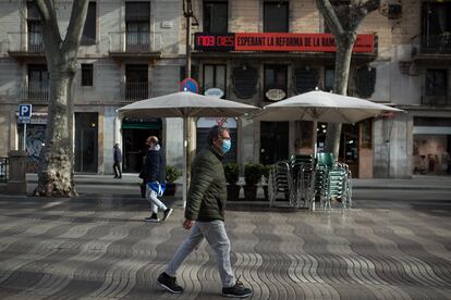 Varias personas caminan por la Rambla, de fondo, el cartel que recuerda los días transcurridos desde que se anunció la reforma