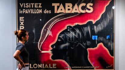 Una joven frente al cartel de la Exposición Colonial de París de 1931, que emplea el icono de la mujer mangbetu, este miércoles en el IVAM.