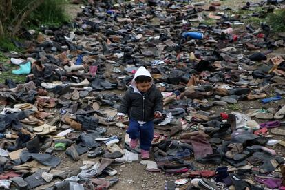 Un niño corretea entre calzado desechado, en el campamento de Moria.
