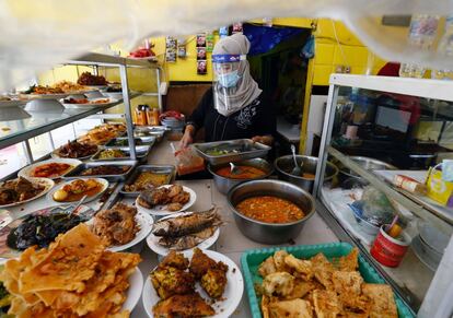 Una mujer protegida contra el coronavirus trabaja en el interior de una tienda de comida precocinada en Jakarta (Indonesia). El país ha superado los 100.000 casos de coronavirus y suma 4.838 fallecidos.