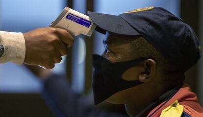 Un sanitario realiza una prueba de temperatura a un policía en Johanesburgo (Sudáfrica). 