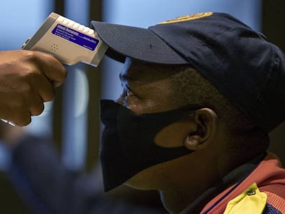 Un sanitario realiza una prueba de temperatura a un policía en Johanesburgo (Sudáfrica). 