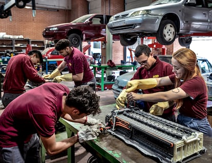 Alumnos de FP manipulando una batería híbrida durante una clase de electromecánica de vehículos en el IES Benicalap de Valencia.