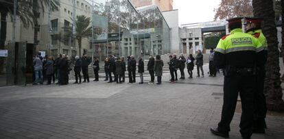 Dos mossos d'esquadra observan la cola de electores en un colegio.