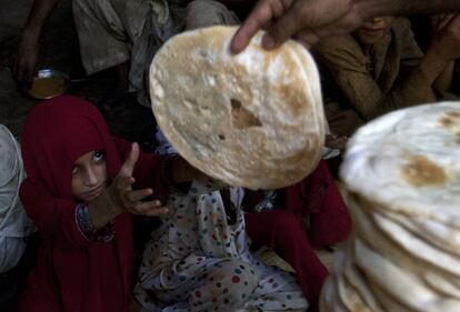 Una niña extiende su mano para coger una torta de maíz en un centro de distribución de alimentos en Karachi (Pakistán).