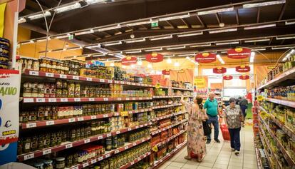 Varios consumidores compran alimentos en un supermercado.  