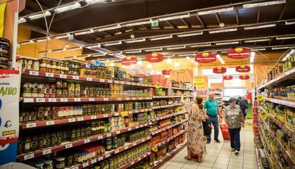 Varios consumidores compran alimentos en un supermercado.