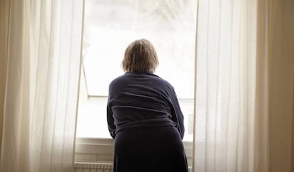 Una mujer asomada a una ventana, en una imagen de archivo.