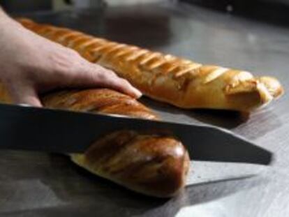 Un repostero corta una barra de pan en una pastelería de España.