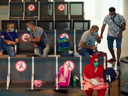 Viajantes com máscaras protetoras aguardam seu voo no aeroporto de Barcelona.