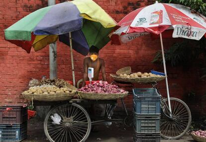 Un vendedor de verduras usa una mascarilla protectora mientras espera a los clientes en Kolkata, India, el 17 de julio de 2020. 