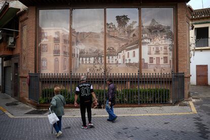 Tres personas pasean junto a un mural en relieve en la plaza de la Constitución de Maracena (Granada).