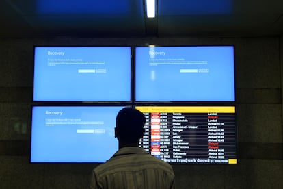 A passenger looks at malfunctioning information screens, at the Delhi International airport in New Delhi, India, 19 July 2024.