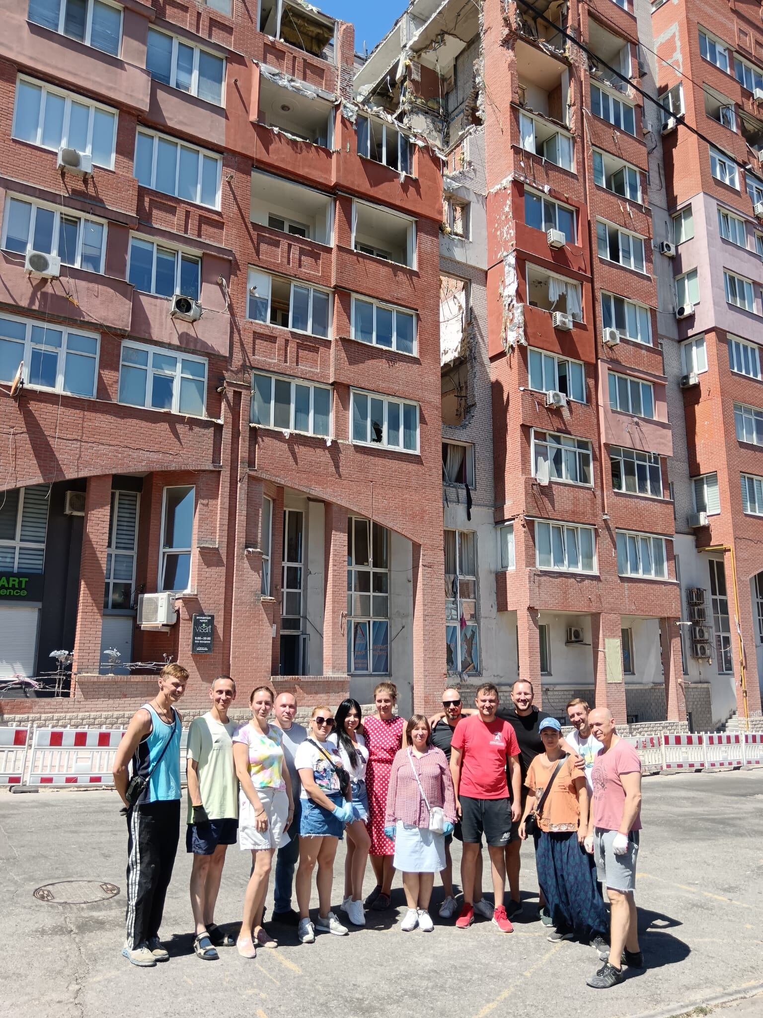 Um grupo de colegas de trabalho posou no dia 13 próximo à entrada de um prédio da cidade ucraniana de Dnipro que foi atingido por um míssil.