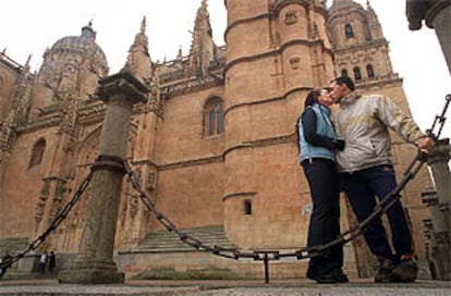 Una pareja se besa delante de la catedral de Salamanca.